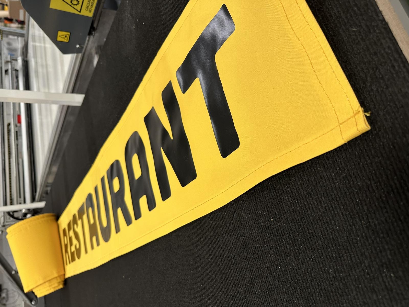Store banne personnalisé : lambrequin de restaurant floqué en noir sur toile jaune
